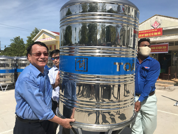  Ông Vũ Ngọc Sơn - chủ tịch hội đồng quản trị Hải An Group (trái) - tiếp tay khiêng bồn chứa nước lên xe chở đến nhà dân - Ảnh: KHẮC TÂM